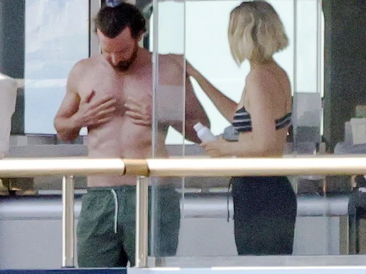 Gigi Hadid applying sunscreen on Bradley Cooper