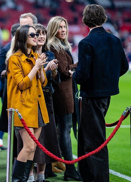 Olivia Rodrigo and Louis Partridge standing on the field at Old Trafford Stadium