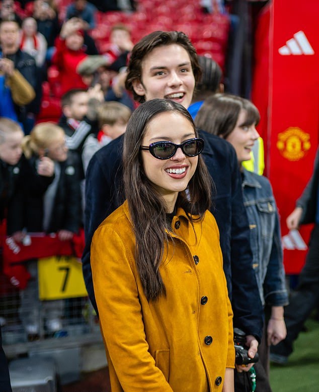 Olivia Rodrigo and Louis Partridge watching a football match at Old Trafford Stadium in Manchester